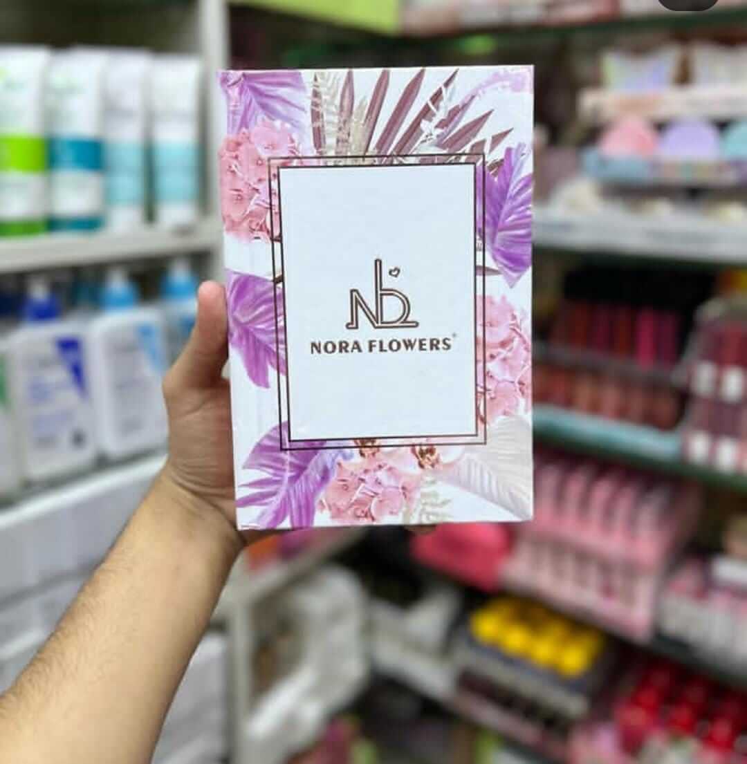 Nora Flowers product packaging displayed in a hand, featuring floral design and logo, set against a store background.